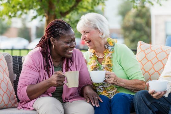 Two women laughing with each other, holding mugs